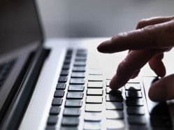Close up of man's fingers typing on computer