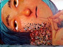Grafite da artista Mag Magrela, de um rosto de mulher, com azulejos