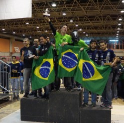 Membros da equipe Troia no pódio, segurando o troféu e bandeiras do Brasil