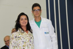Professora Joziana Barçante faz a entrega do jaleco branco com a logomarca UFLA - prática tradicional dos cursos de Medicina.