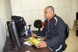 O entrevistado Nilmar Machado está sentado à frente do computador,.